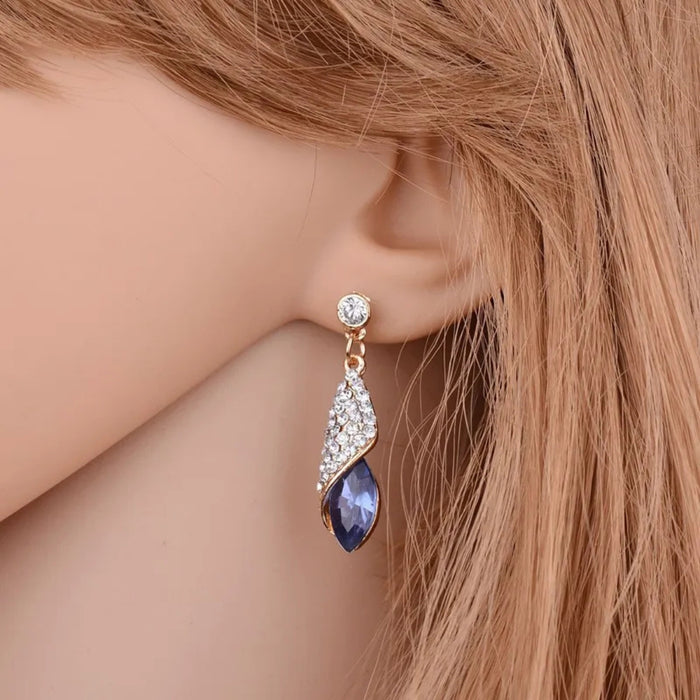 Earring with a blue gemstone worn on a mannequin ear