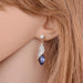 Earring with a blue gemstone worn on a mannequin ear