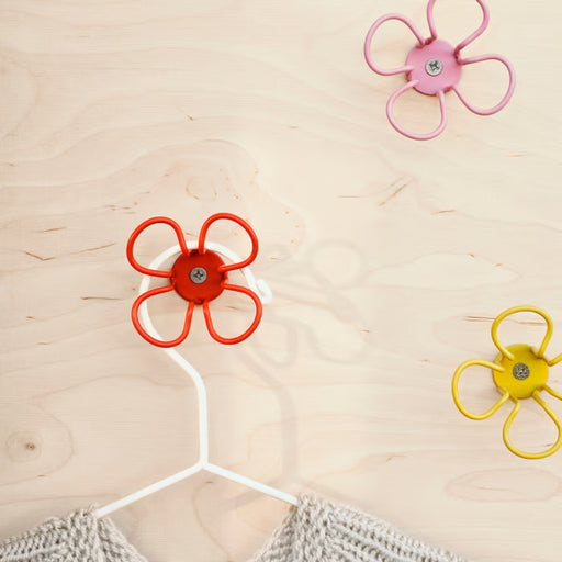 Green circular OMMJÄNGE hook mounted on a white wall holding a small colorful bag.
