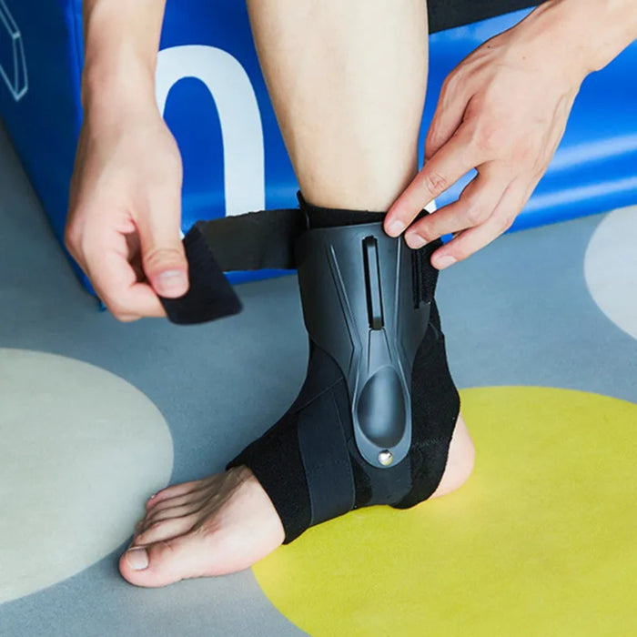 Person adjusting a black ankle support brace on a colorful floor.