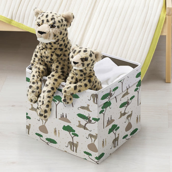 Two plush toy leopards in a box with animal print design on a light wooden floor.