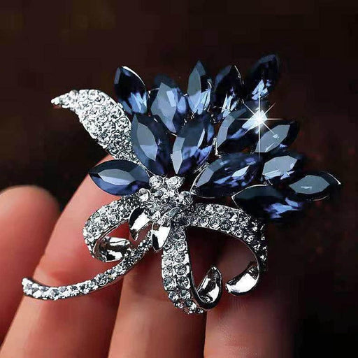Crystal brooch – held in hand showing dark blue petals and rhinestone-encrusted bow