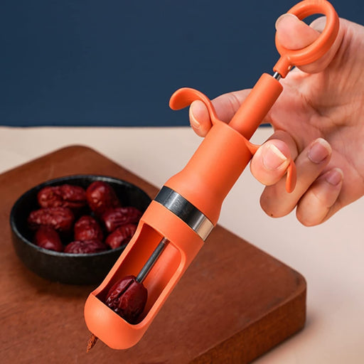 Hand using orange jujube pitter to remove seed from date, with bowl of dates in background