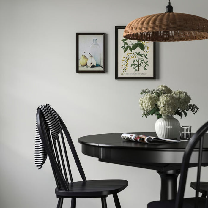Stylish dining area with black round table, white vase of hydrangeas, and two framed artworks on wall - 70327189