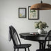 Stylish dining area with black round table, white vase of hydrangeas, and two framed artworks on wall - 70327189