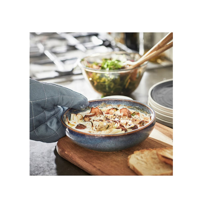 Bowl of soup with a hand holding a spoon, kitchen setting