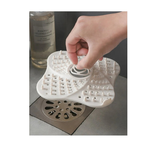 Hand placing a white silicone drain cover over a sink drain.