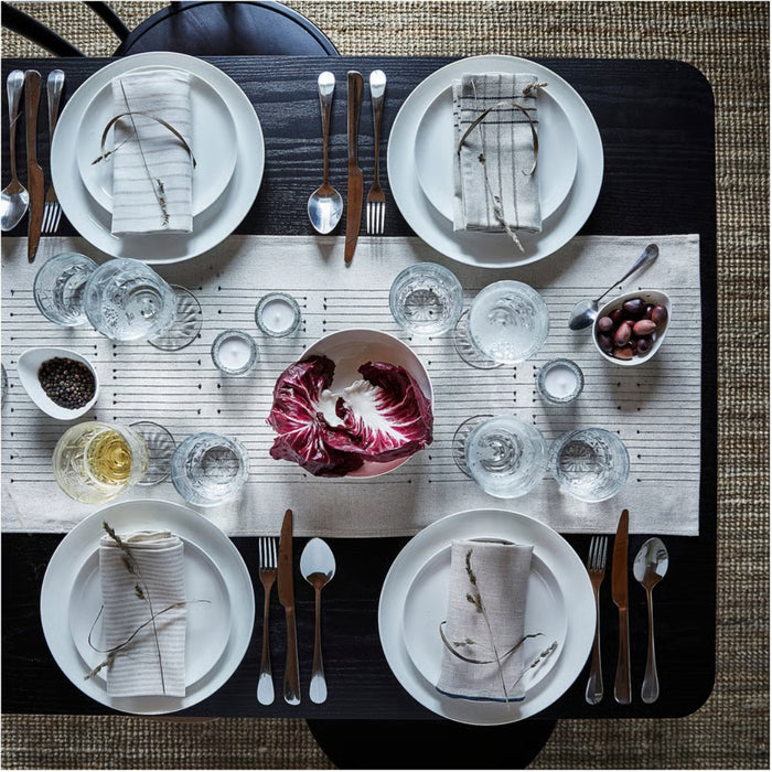 Elegant table setting with white plates, silverware, and a centerpiece on a textured surface.