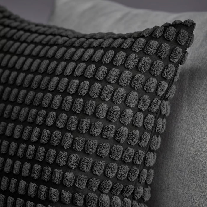 Close-up of SVARTPOPPEL cushion cover showing evenly spaced raised oval tufts on black background, highlighting textured design