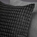 Close-up of SVARTPOPPEL cushion cover showing evenly spaced raised oval tufts on black background, highlighting textured design