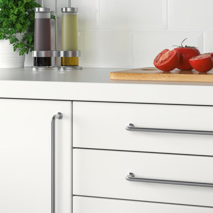 White kitchen cabinets with silver handles, a cutting board with tomatoes, and jars on a countertop.