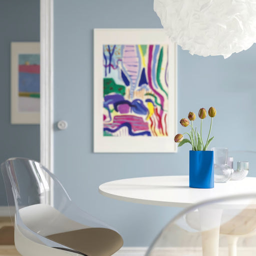 Modern dining room with a round table, clear chair, and colorful abstract art on the wall.
