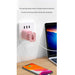Wall-mounted charging station with pink cup holder, smartphone, and laptop on a wooden surface.