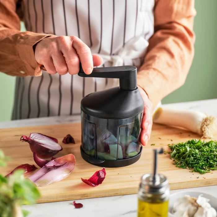 STENSNULTRA chopper in use on wooden cutting board, chopping red onions with herbs and vegetables nearby
