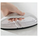 Hand holding a white iron on a light gray background