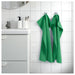 Green towels hanging on a towel rack in a bathroom with white tiles.