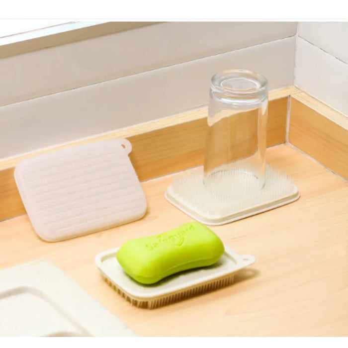 Green bar of soap on a white soap dish with a glass of water and a white cloth in the background.