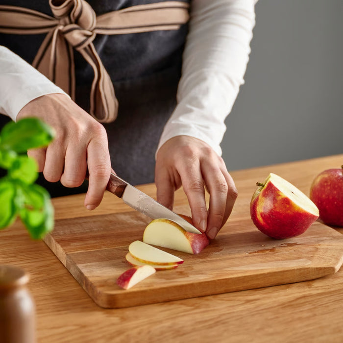 Person slicing apples on a wooden cutting board with a blurred background