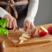 Person slicing apples on a wooden cutting board with a blurred background