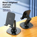 Two black metal phone/tablet stands with dual-axis rotation placed on a wooden surface—labeled “Metal weighted dual axis rotation” and “Mobile phone/tablet universal” – 1600006845076 13109076.