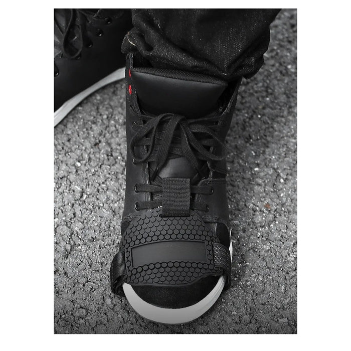 Black high-top sneaker with white sole on a gray pavement background