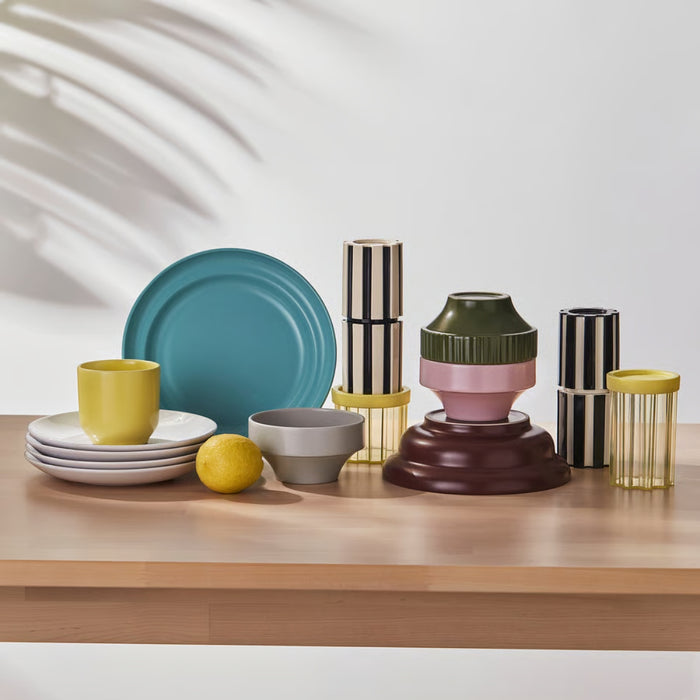 SPJUTLILJA bowls arranged with plates and cups in colorful kitchenware display, stacked with striped containers and lemon accent