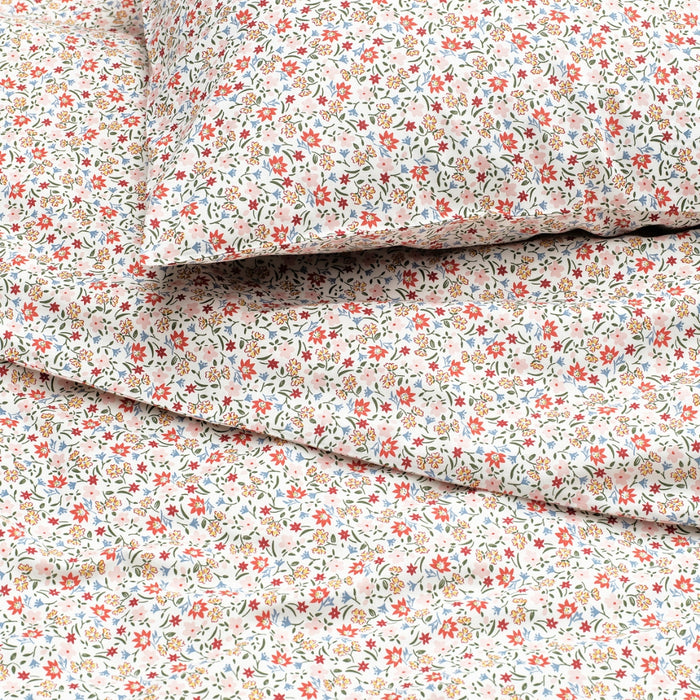 “Bed dressed in white duvet cover and pillowcases with colourful floral print, creating a fresh and cozy bedroom look.”

