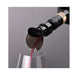 Wine bottle being uncorked with red wine pouring into a glass on a gray background
