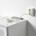 FÖRNIMMA power supply cord, 3.5 m (138"), white – coiled cord placed on a white cabinet, plugged into a dual wall socket. Ideal for connecting up to 10 integrated lamps – 50446876.