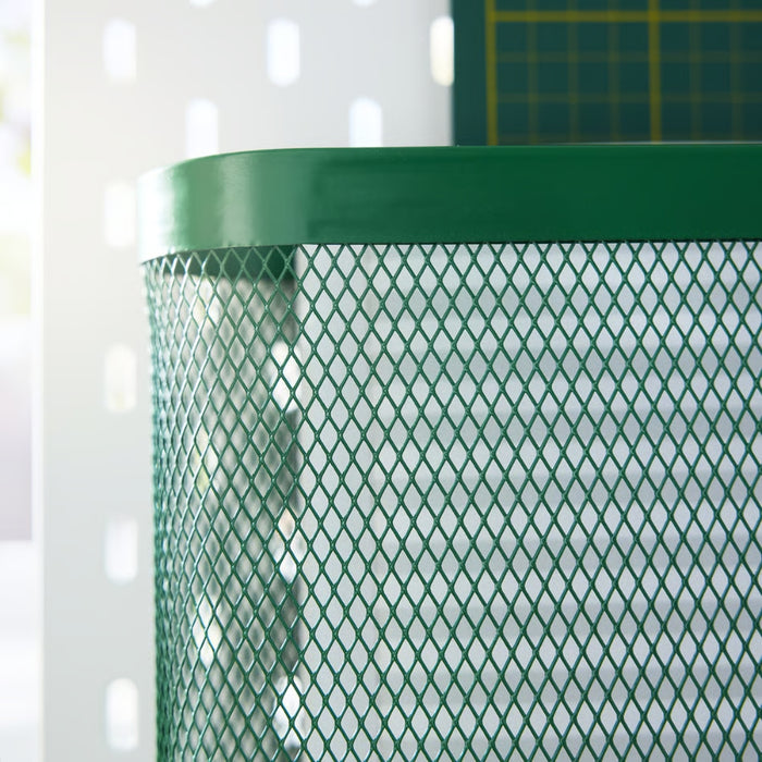 Close-up of IKEA SKÅDIS green mesh storage basket mounted on white perforated pegboard; cylindrical design with diamond-patterned texture beside green cutting mat – part of 3-piece organizer set for creative workspaces - 20597471