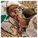 Child lying in bed holding a teddy bear with animal-themed bedding