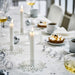 Elegant celebration setup featuring FRÖJDA holders with white candles, desserts, and sparkling drinks in a winter-themed arrangement