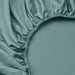 Close-up of teal NATTJASMIN fitted sheet with gathered elastic edges; smooth, lustrous fabric in cotton/lyocell blend 