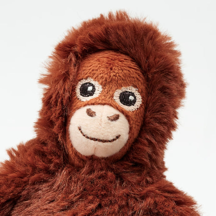 Close-up of orangutan plush toy showing fuzzy reddish-brown fur and embroidered facial details.

