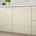 Beige kitchen cabinets with a white countertop and tiled backsplash.