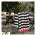 Striped blanket draped over a chair with outdoor furniture and plants in the background