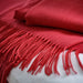 Close-up of red woven throw with detailed fringe, highlighting cozy fabric and rich seasonal tone