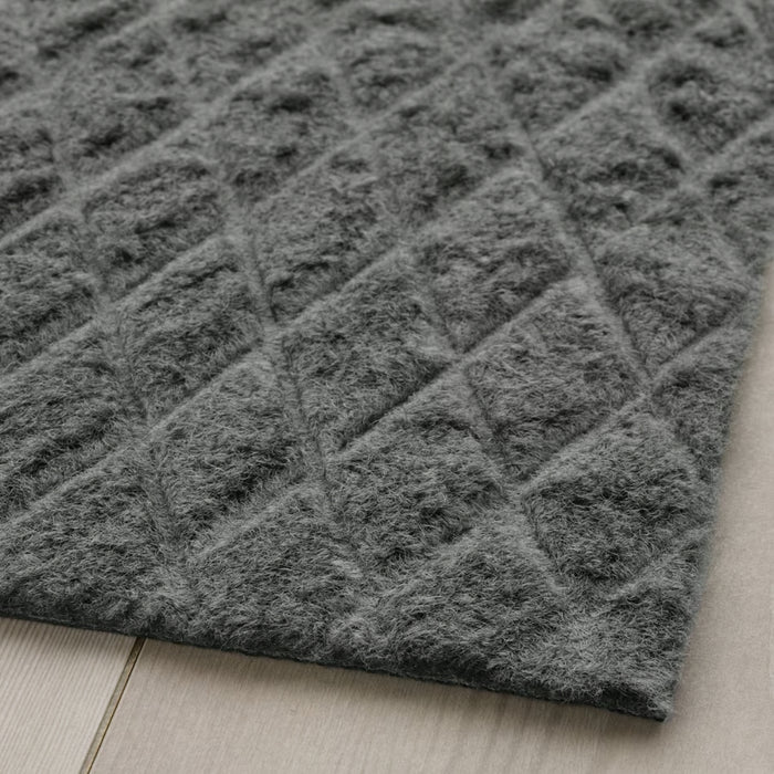 Close-up of IKEA ÖSTERILD indoor door mat in dark grey with raised diamond texture; soft surface placed on light wood floor – 60511116