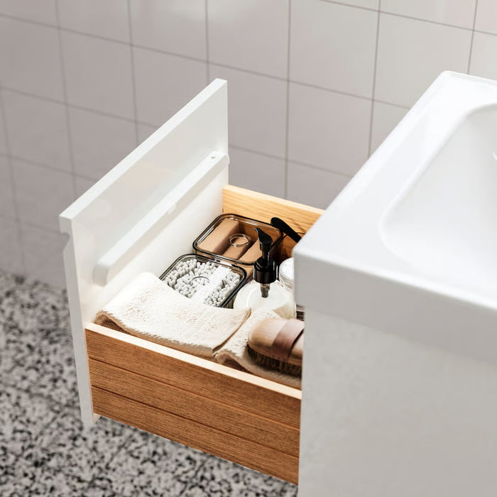 Open wooden cabinet under a sink with toiletries in a bathroom setting.