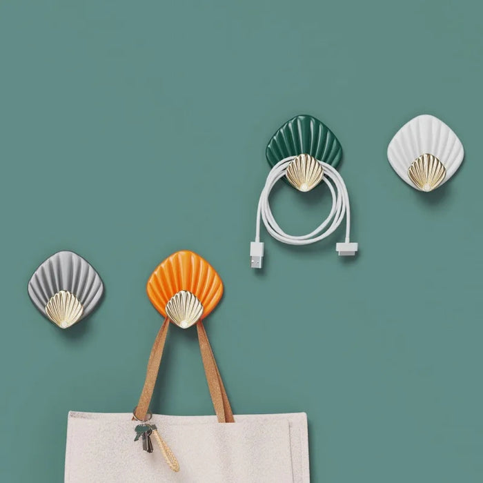 Shell-shaped wall hooks on a green background with a bag and cable.
