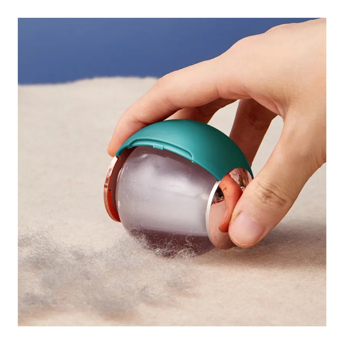 Hand using a small roller device on fabric with a blue background