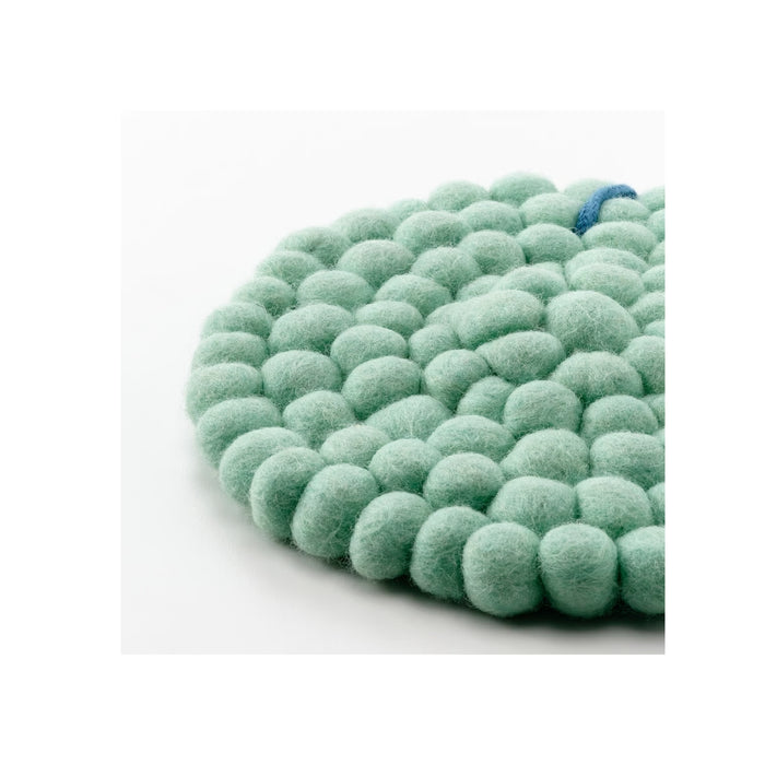 Green felt ball rug on a white background
