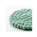 Green felt ball rug on a white background