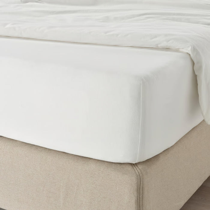 White fitted sheet on a beige bed