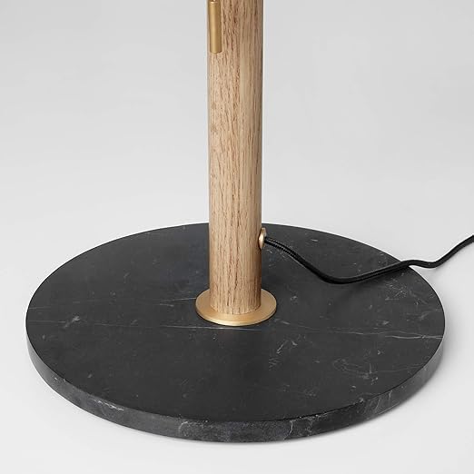 Floor lamp with wooden pole and black marble base on a light gray background