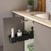 Kitchen cabinet with a black caddy holding cleaning supplies next to a sink.