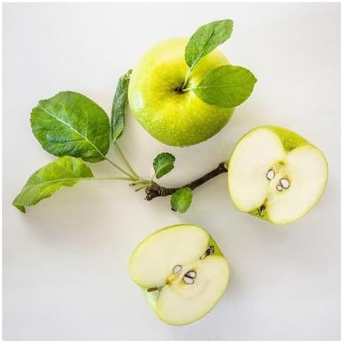 Whole and halved green apples with leafy branch arranged on white surface – 50582053