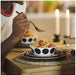 Dining scene featuring a person enjoying spaghetti with meatballs from an IKEA OFTAST bowl—white bowl adorned with black polka dots is placed on a black plate with a woven placemat underneath.-10608267