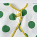 IKEA KLADDIG bib laid flat—white base with large green polka dots, yellow trim forming side ties and neckline loop, ideal for toddlers during mealtime or play – 70607142.