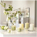 Decorative setup with lit green and white candles, blooming branches, and green apples – 50582053